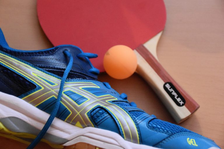 blue and black ASICS running shoes near ping pong paddle and ball